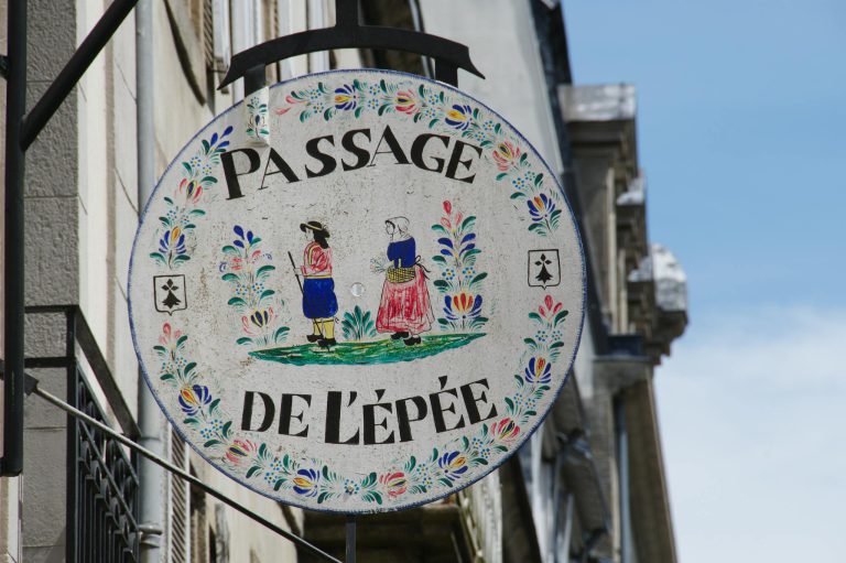 Colorful decorative sign 'Passage de l'Épée' in Quimper, France, showcasing traditional clothing art.
